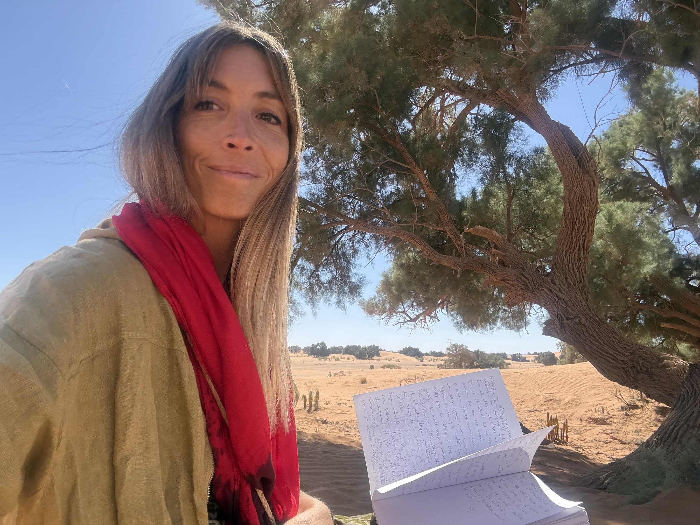 La Dra. Florencia López escribiendo en su libreta bajo un árbol del desierto